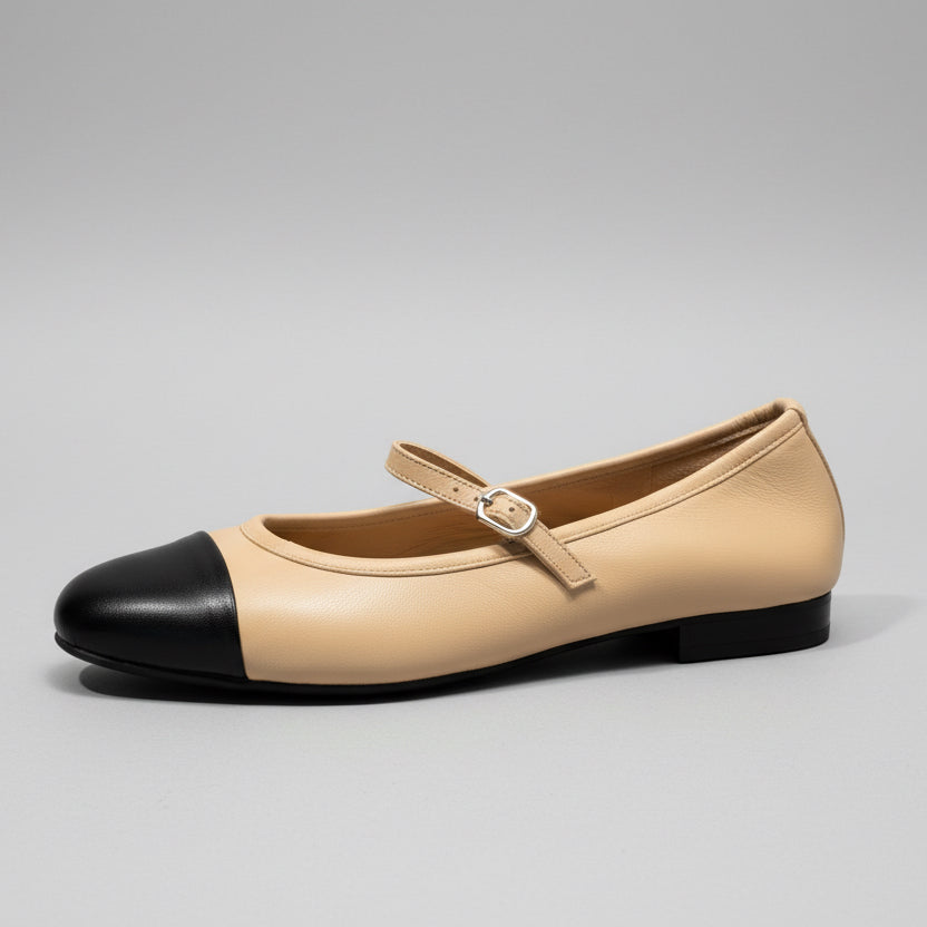 Beige ballet flat shoe with black heel on a wooden surface