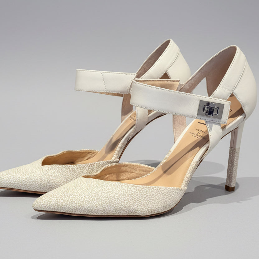 Pair of beige high-heeled shoes on a wooden surface with a neutral background
