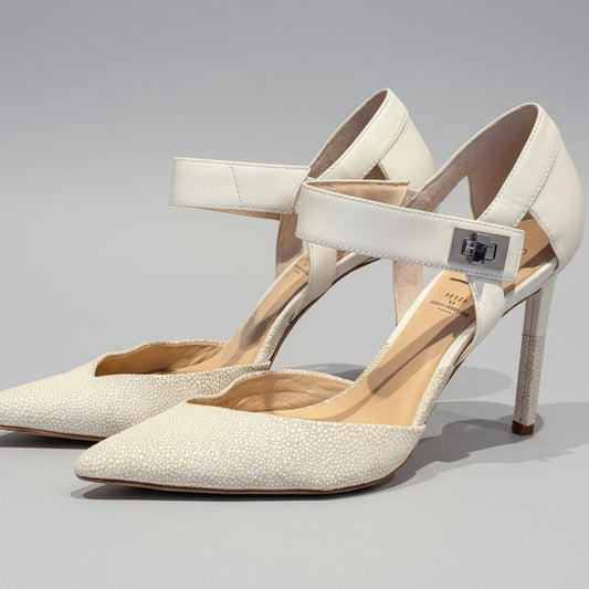 Pair of beige high-heeled shoes on a wooden surface with a neutral background