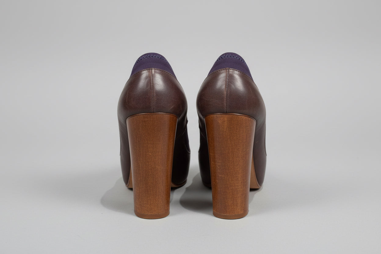 Pair of brown high-heeled shoes on a wooden surface with a white background