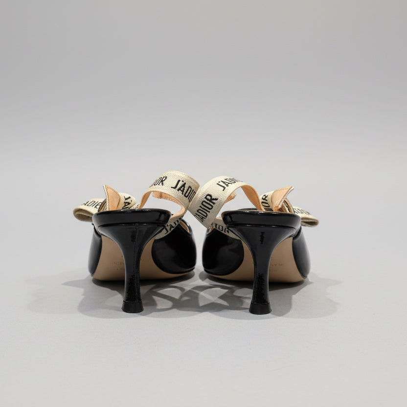 Pair of black high-heeled shoes with bow details on a wooden surface