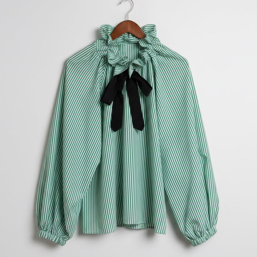 Green and white striped dress with black bow on a beige background