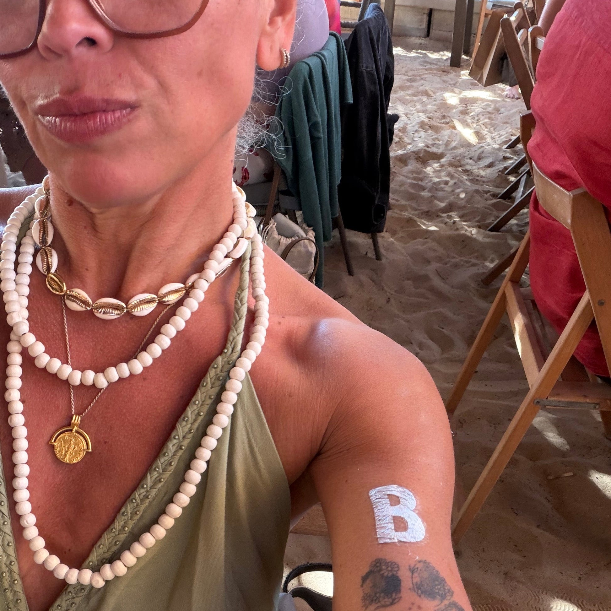 Woman with arm tattoo and necklace in a casual setting