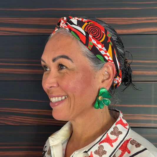 Woman wearing a colorful headscarf and earrings with a patterned background