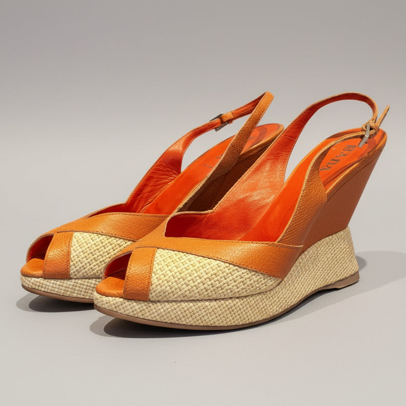 Orange wedge sandals with woven design on a wooden surface