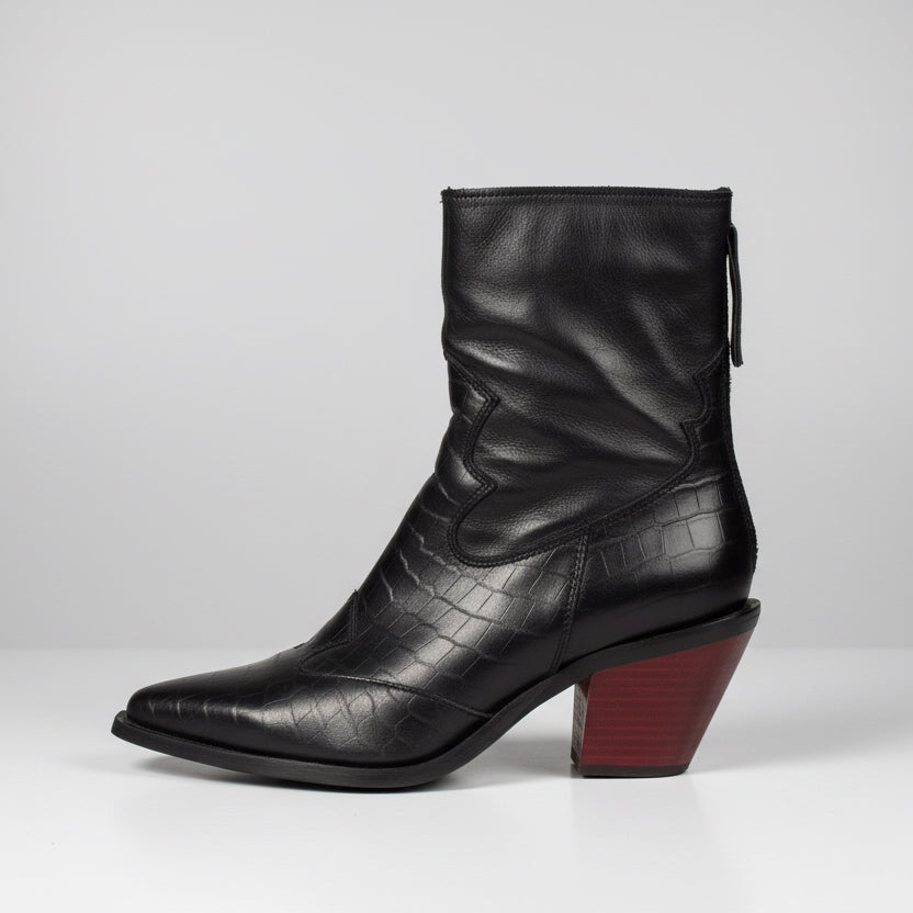 Black leather boot with a block heel on a wooden surface