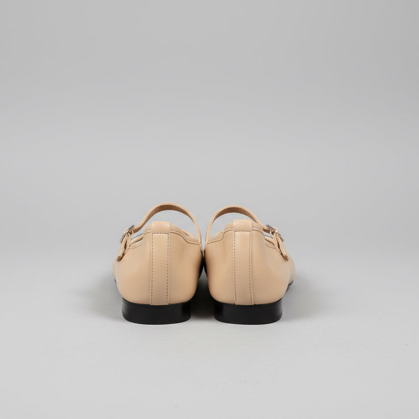 Pair of beige shoes on a wooden surface with a neutral background