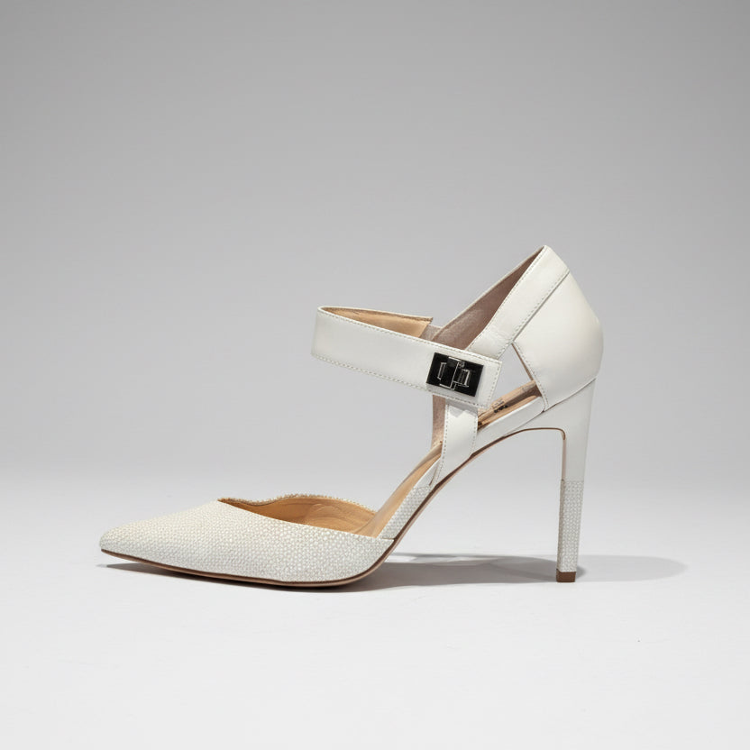 White high-heeled shoe with a strap on a wooden surface