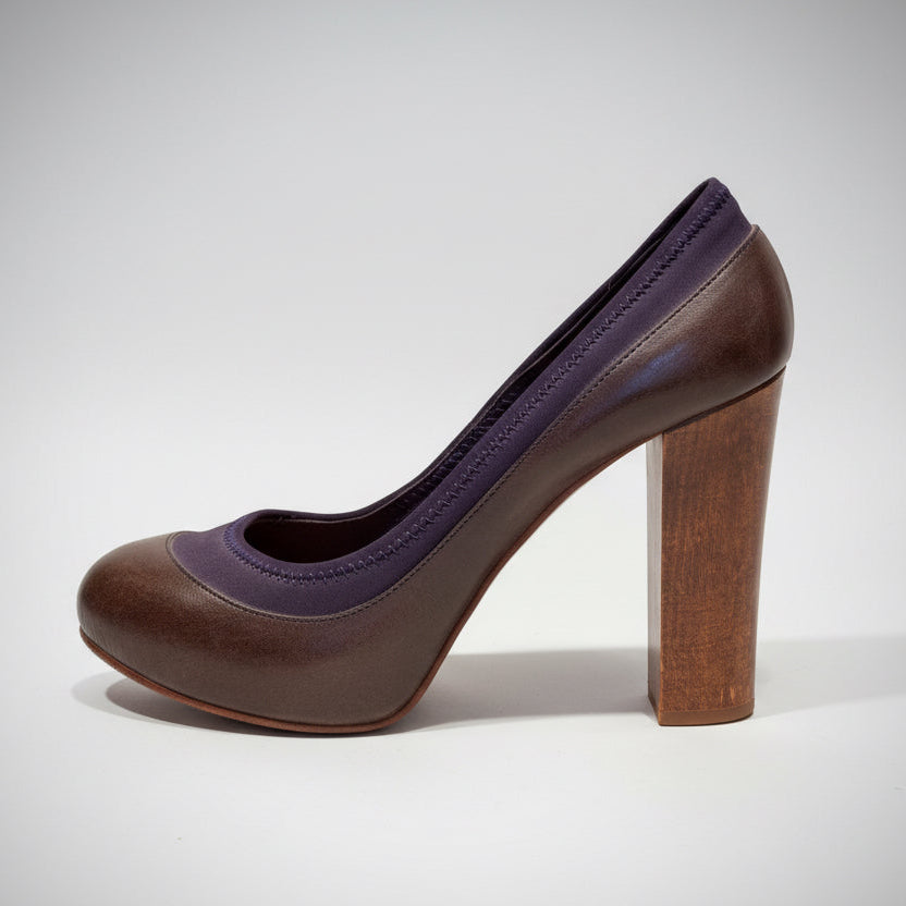 Brown high-heeled shoe on a wooden surface with a white background