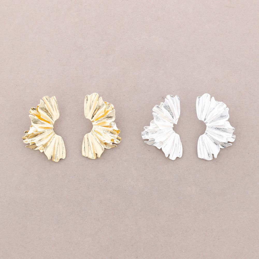 Pair of gold earrings and pair of white earrings on a beige background