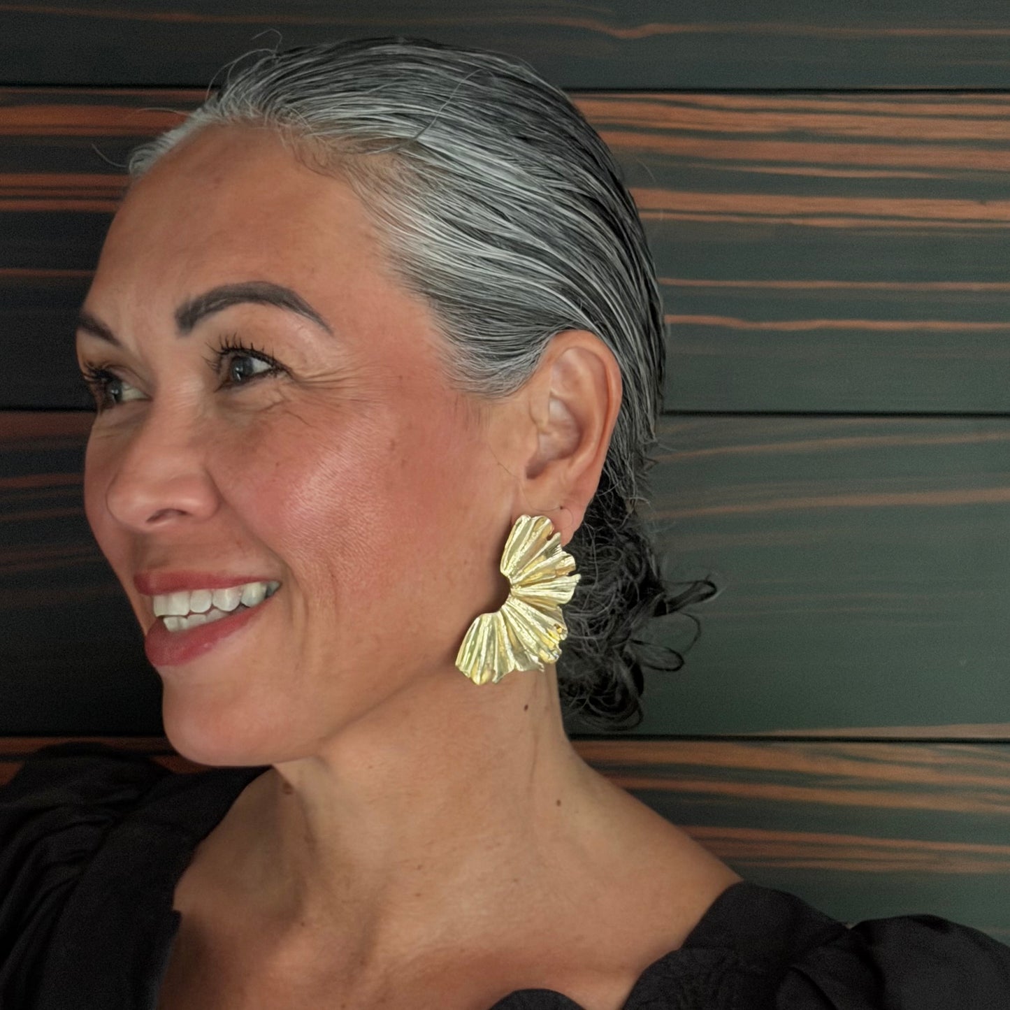 Woman wearing gold earrings against a wooden background
