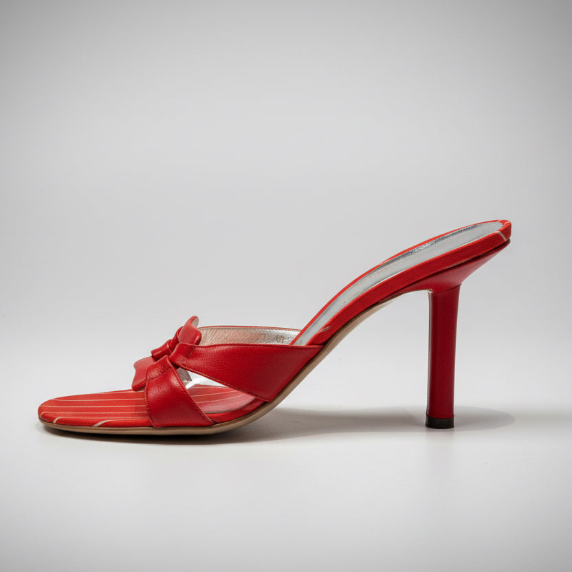 Red high-heeled shoe on a wooden surface with a white background