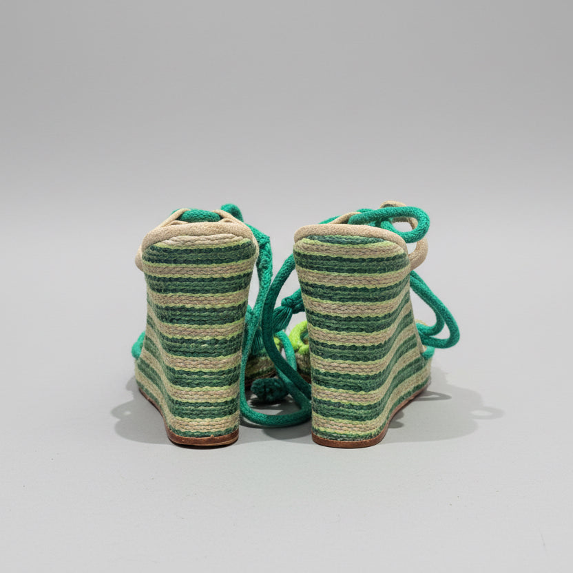Green and beige striped shoes on a wooden surface with a white background