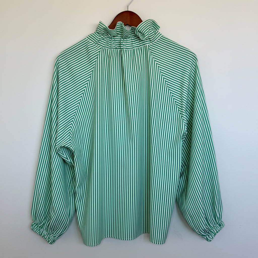 Green and white striped blouse on a wooden hanger against a white background