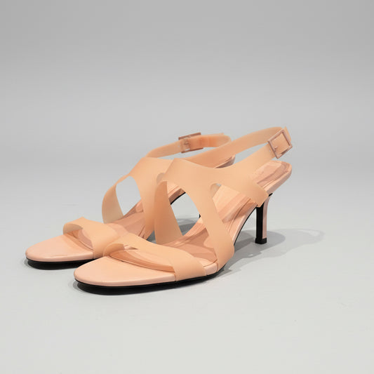 Pair of beige high-heeled sandals on a wooden surface with a neutral background